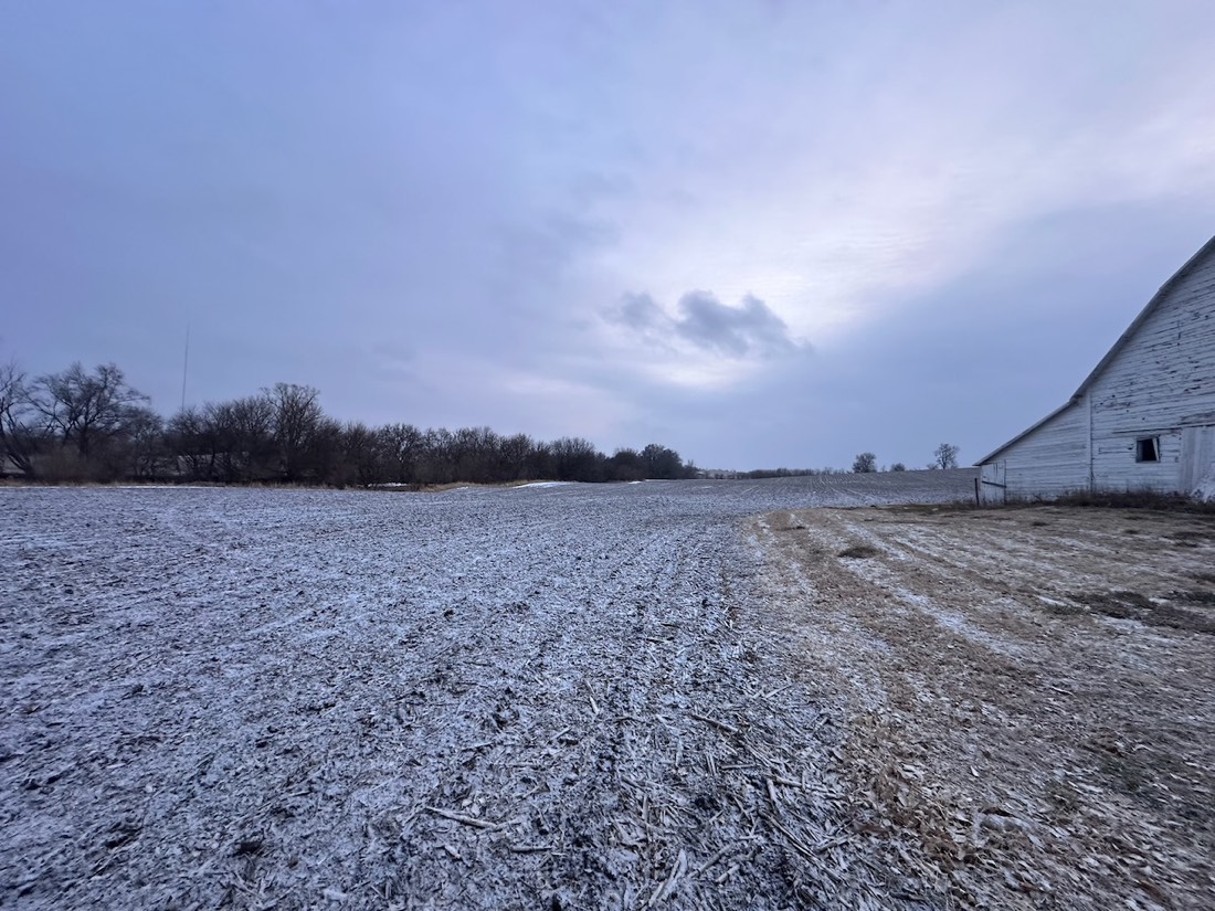The white barn and windmill with bare trees and a dusting of snow.